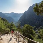 A woman on her way down to the entrance of Samaria Gorge, Crete. The gorge is in southwest Crete in the regional unit of Chania and a major tourist attraction of the island. It was created by a small river running between the White Mountains and Mt. Volakias. The gorge is 16 km long, starting at an altitude of 1,250 m (4100 ft.)at the northern entrance, and ending at the shores of the Libyan Sea in Agia Roumeli.